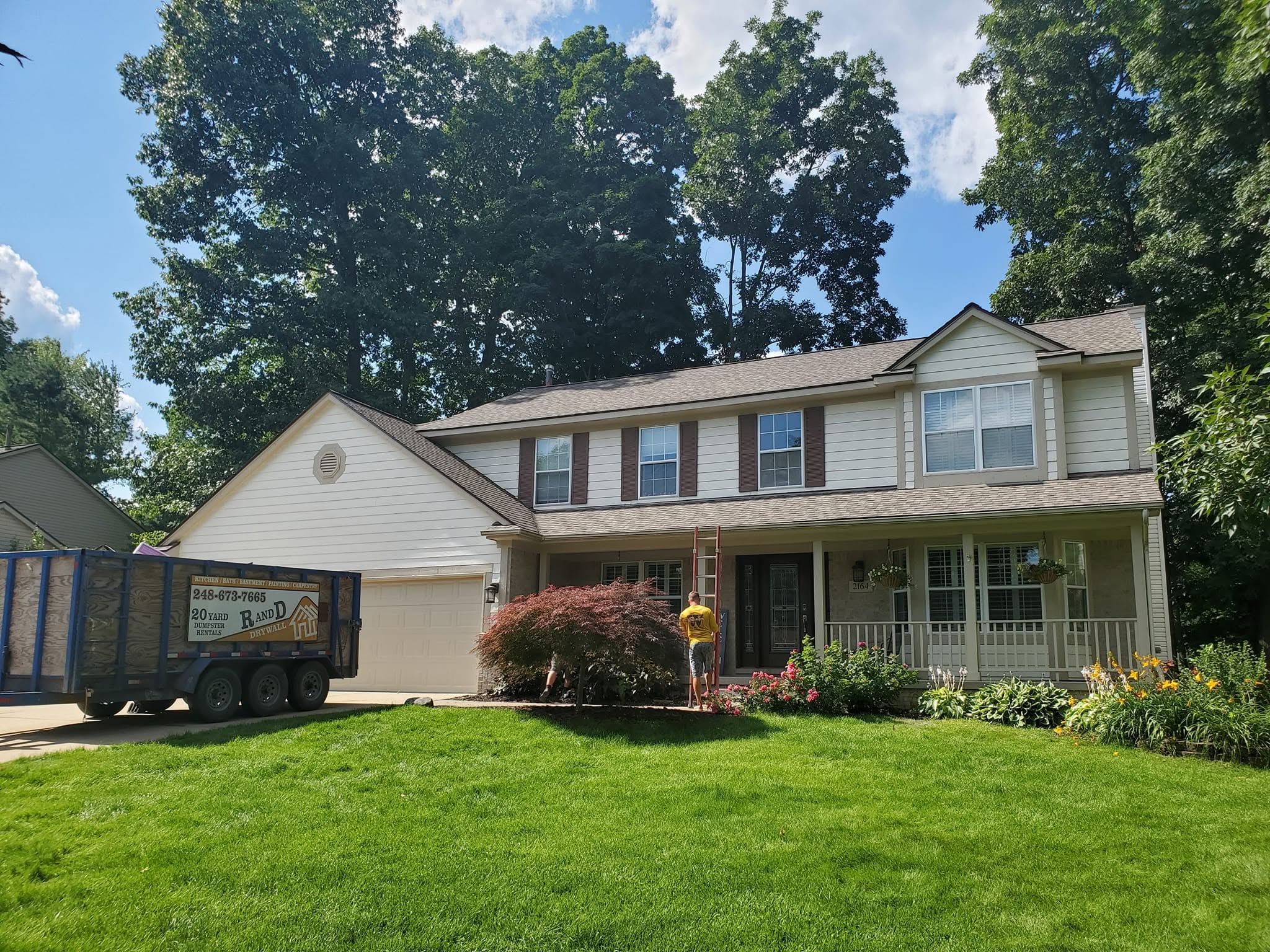 A-Z Roofing crew completing a brown shingle roof on a two-story Michigan home